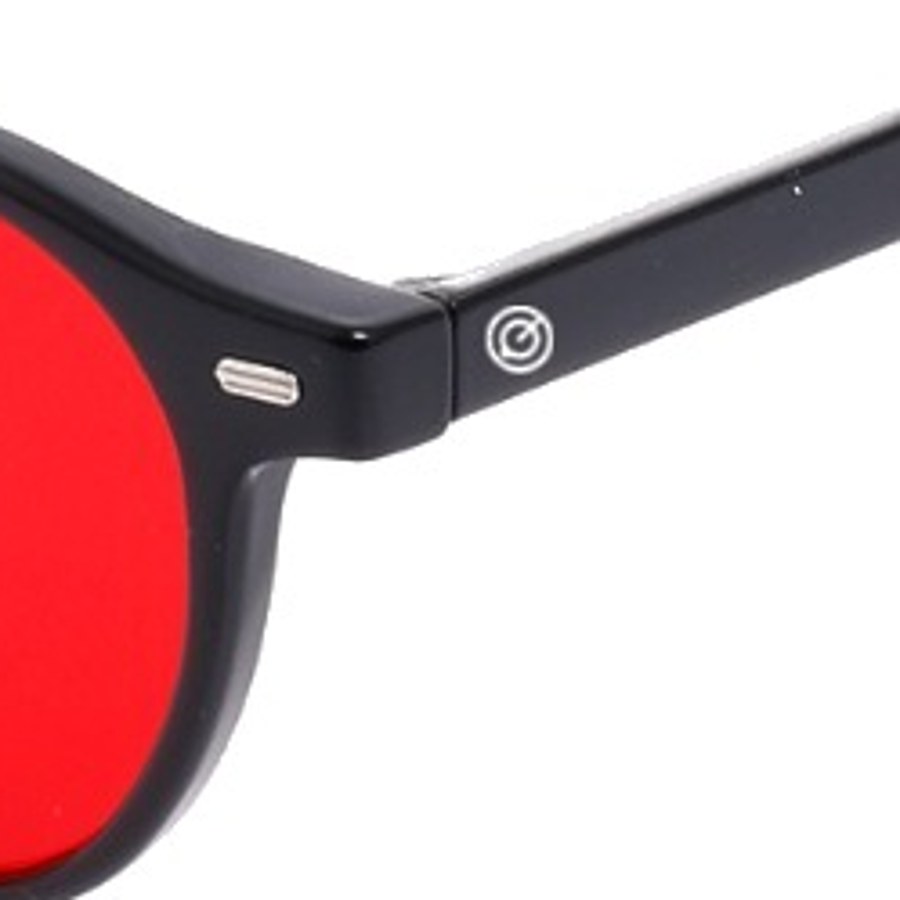 Detalle del lente rojo y la bisagra metálica sobre fondo negro